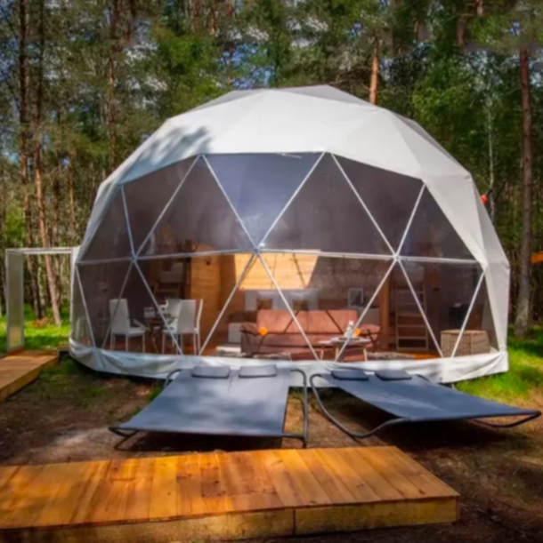 Geodesic dome structure with outdoor furniture in a forest setting