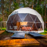 Geodesic dome structure with outdoor furniture in a forest setting