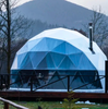 Geodesic dome structure in a natural setting with mountains in the background